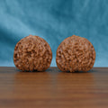 Angled front view of The Amber Sentinels Wenwan walnuts highlighting their rounded forms and warm amber-brown color.
