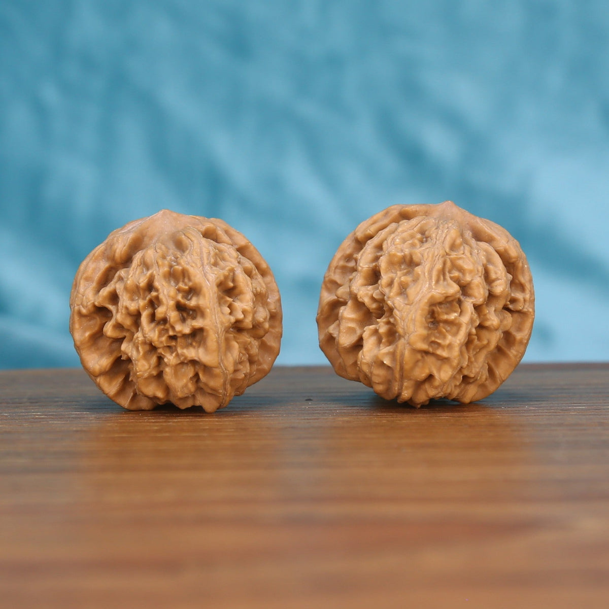 Two Xing-Tai-Yuan-Bao wenwan walnuts on wooden surface, blue fabric background – matching horizon-curve set
