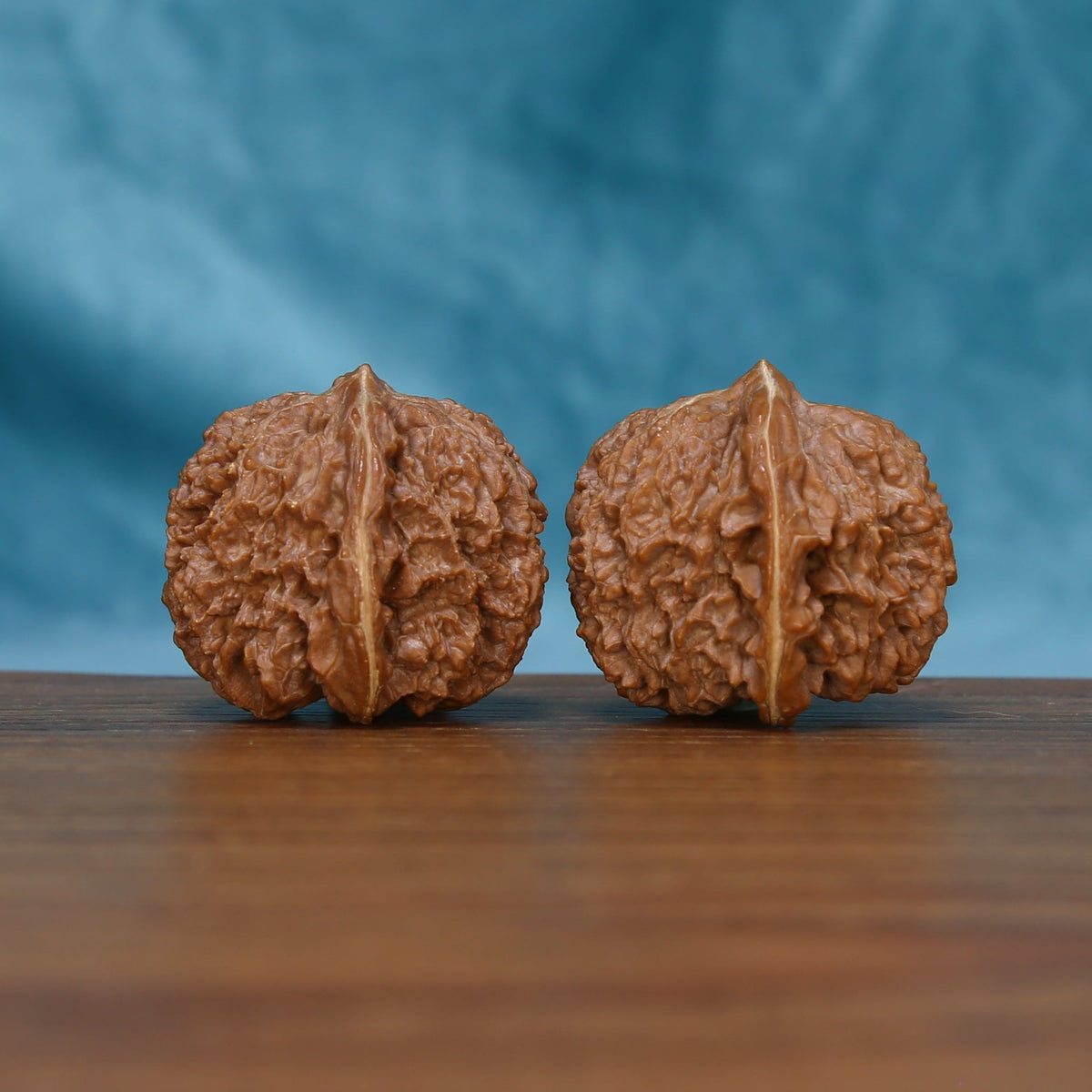 Detailed side view of The Amber Sentinels Wenwan walnuts with pronounced vertical ridges and natural variation.
