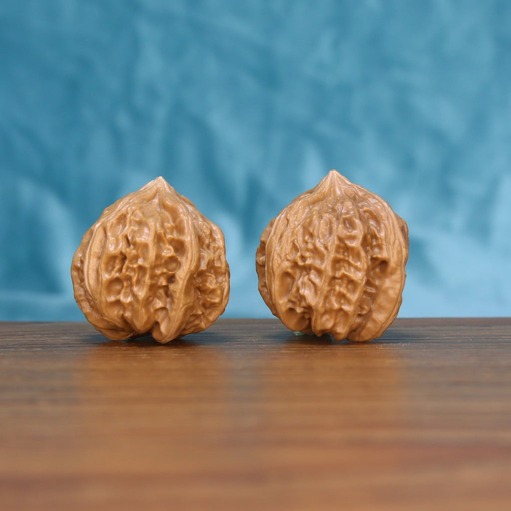 Front view of a matched pair of Four-Ridge Wenwan walnuts with defined natural ridges
