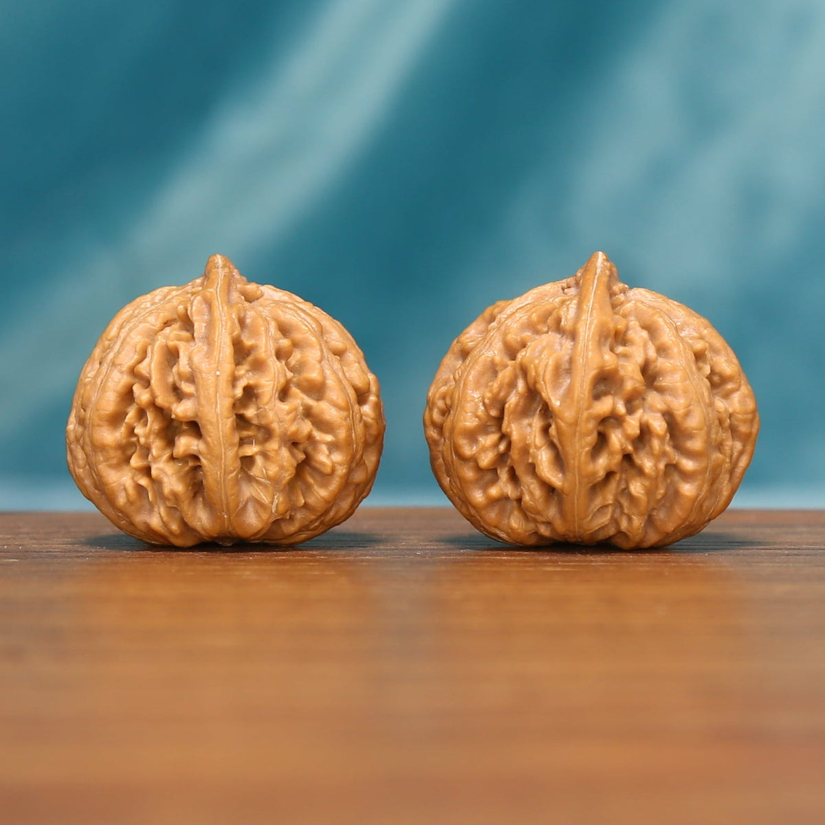 L25 Wenwan walnut pair shown from a textured frontal angle, displaying deep natural ridges and detailed surfaces.
