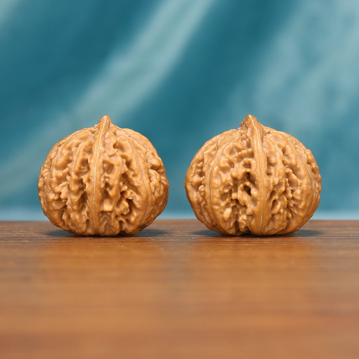 L25 Wenwan walnut matched pair shown side by side in a close view, highlighting rounded shells and symmetrical texture.
