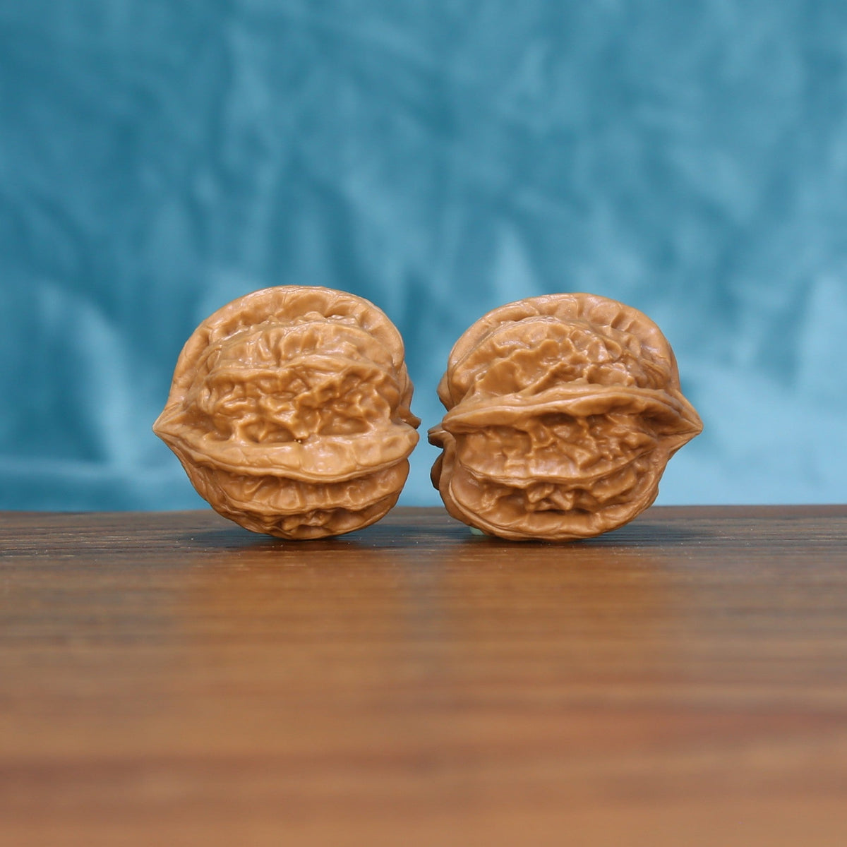 Side view of two Four-Ridge Wenwan walnuts showing their compact sculptural profile
