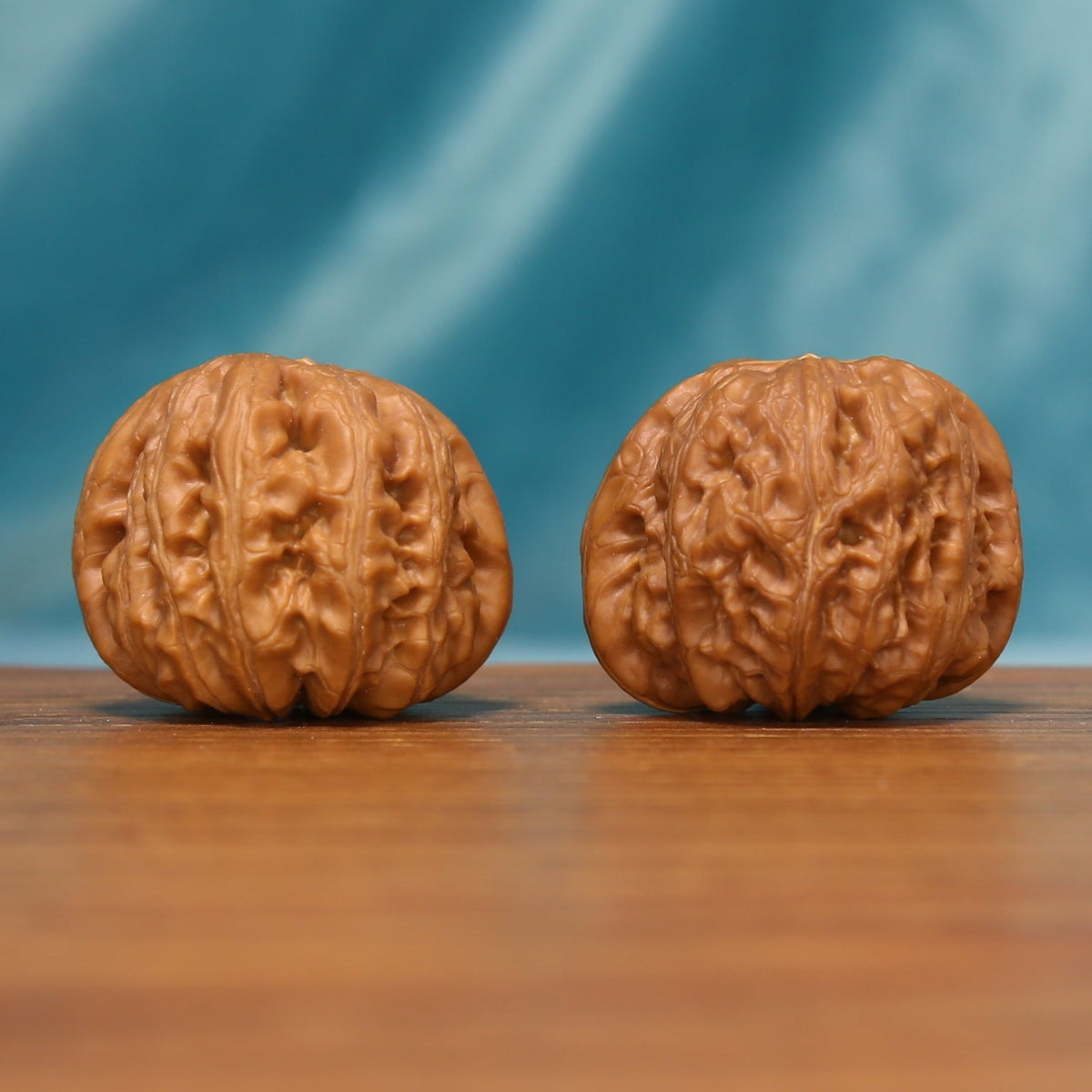 L24 Wenwan walnut pair shown from the front, highlighting their rounded forms and natural ridge texture.
