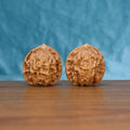 Pair of Linglong Wenwan walnuts standing upright on a wooden surface against a blue background
