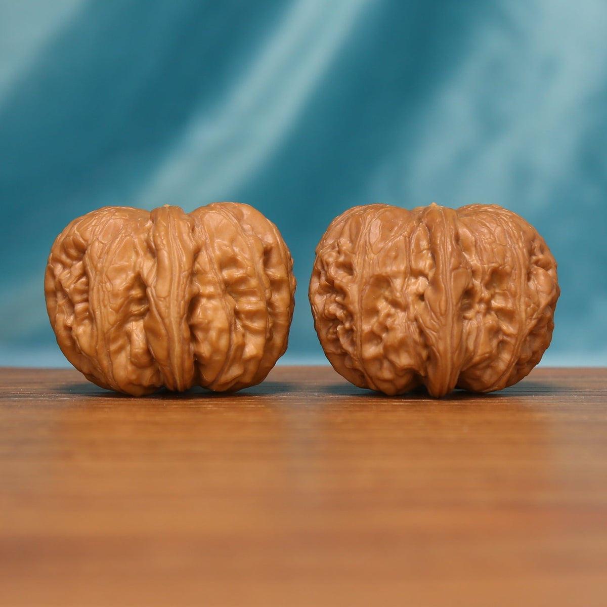 L24 Wenwan walnuts shown side by side from a side angle, highlighting their substantial rounded forms and textured shells.
