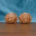 Angled front view of The Ember Pair Wenwan walnuts highlighting their rounded forms and warm natural color.
