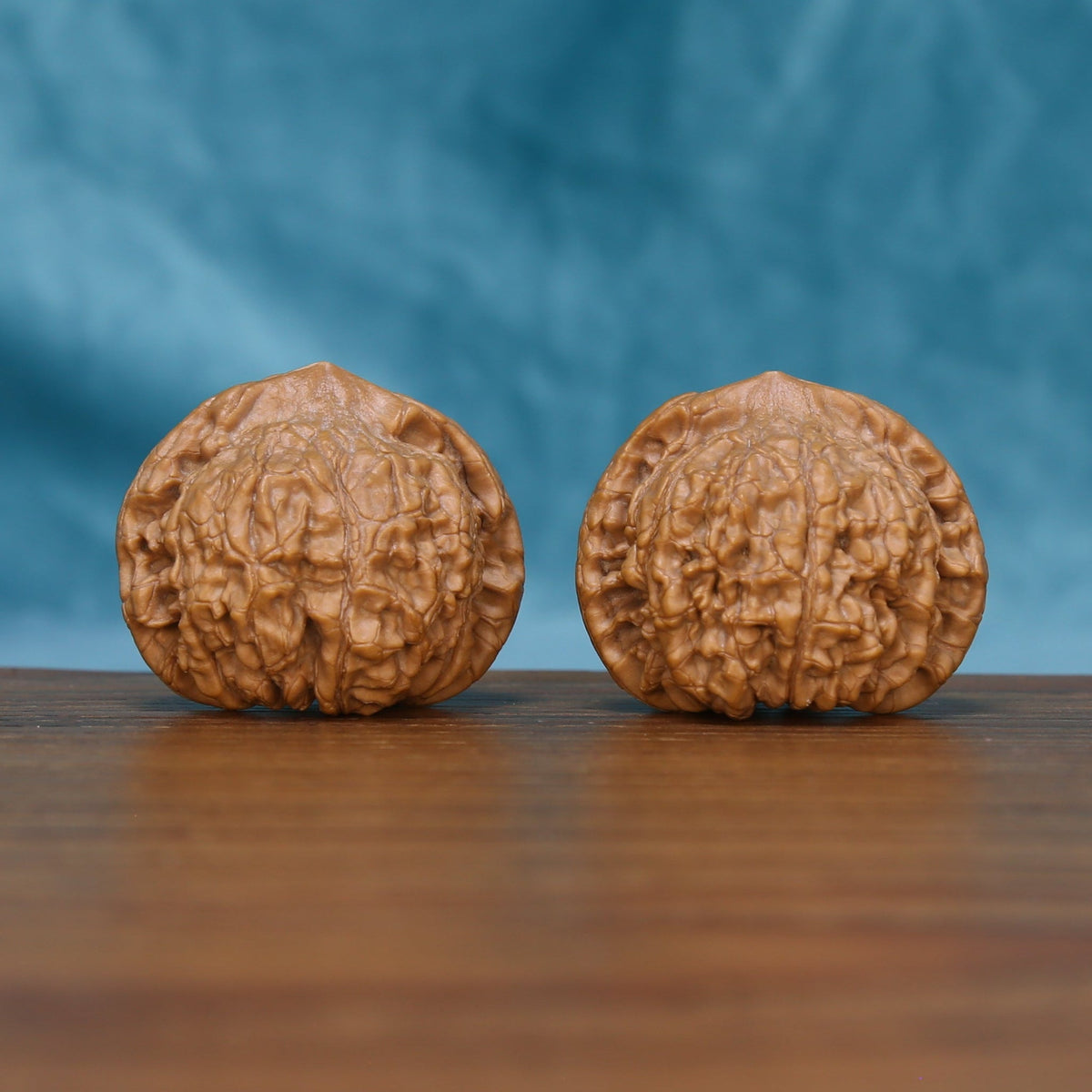 Side view of The Ember Pair Wenwan Walnut Set showing the walnuts’ dense ridge patterns and sculpted profiles.
