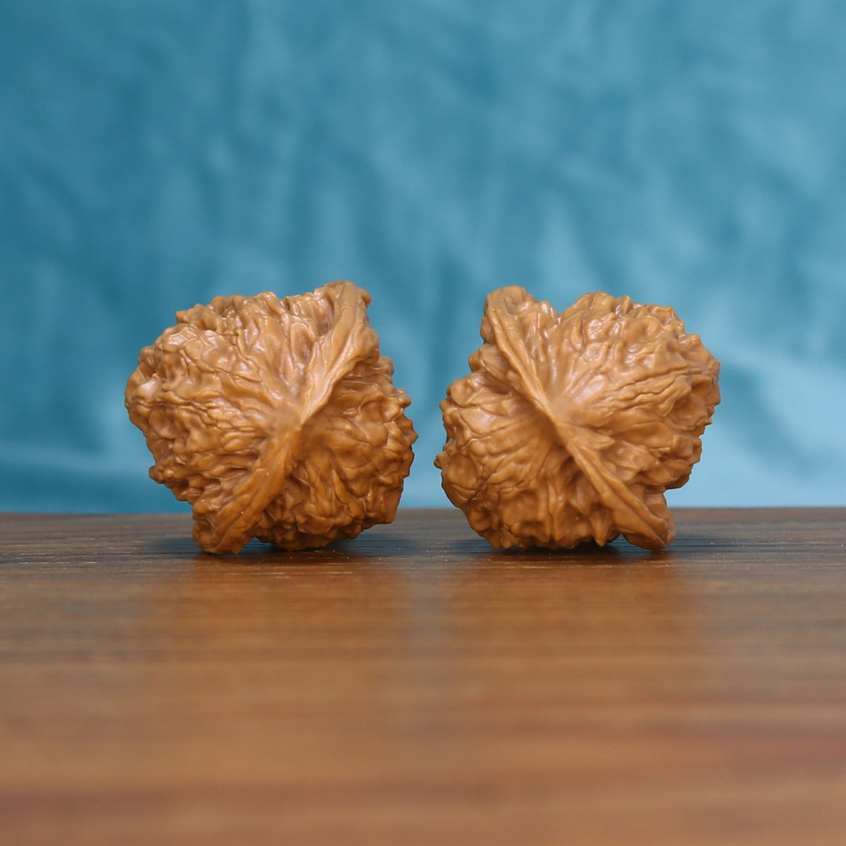 Back view of two Linglong Wenwan walnuts on a wooden surface
