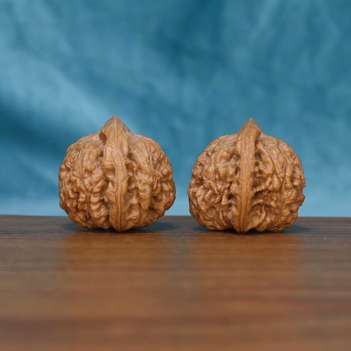 Detailed side view of The Ember Pair Wenwan walnuts with pronounced vertical ridges and natural variation.
