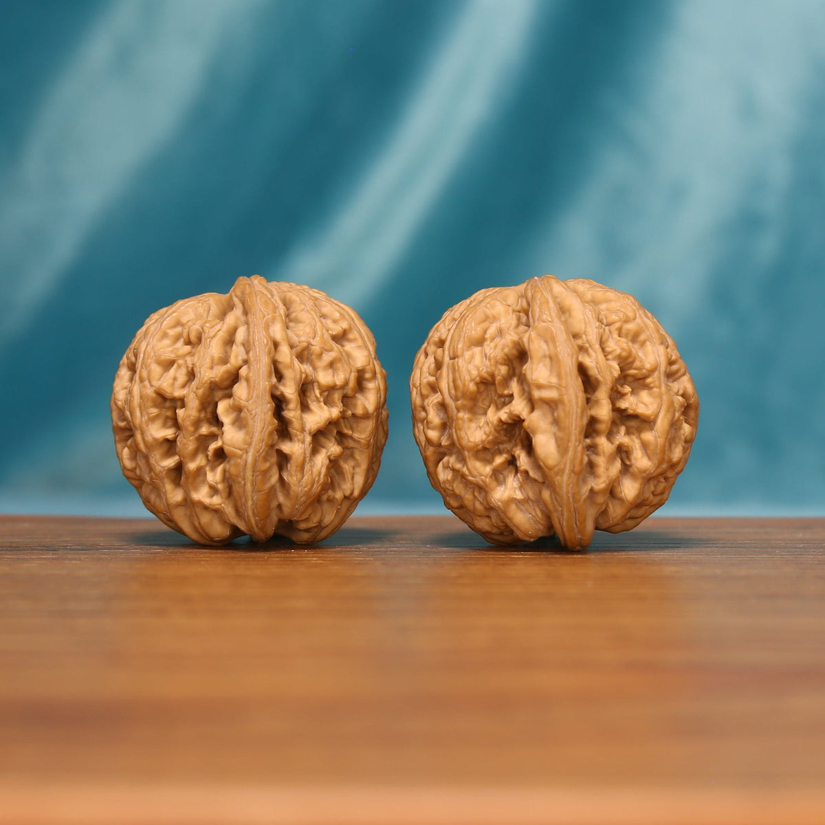 Side view of The Twin Peaks Wenwan walnuts highlighting their rounded profiles and deep natural ridges.
