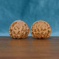 Angled front view of The Ivory Rounds Wenwan walnuts highlighting their balanced shapes and warm natural color.
