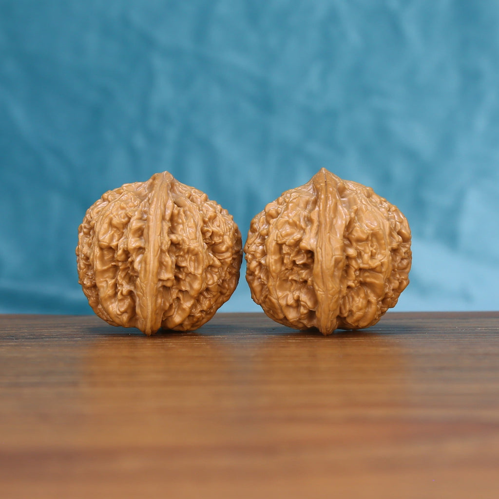 Three-quarter view of two Stone Wenwan walnuts with deep natural ridges
