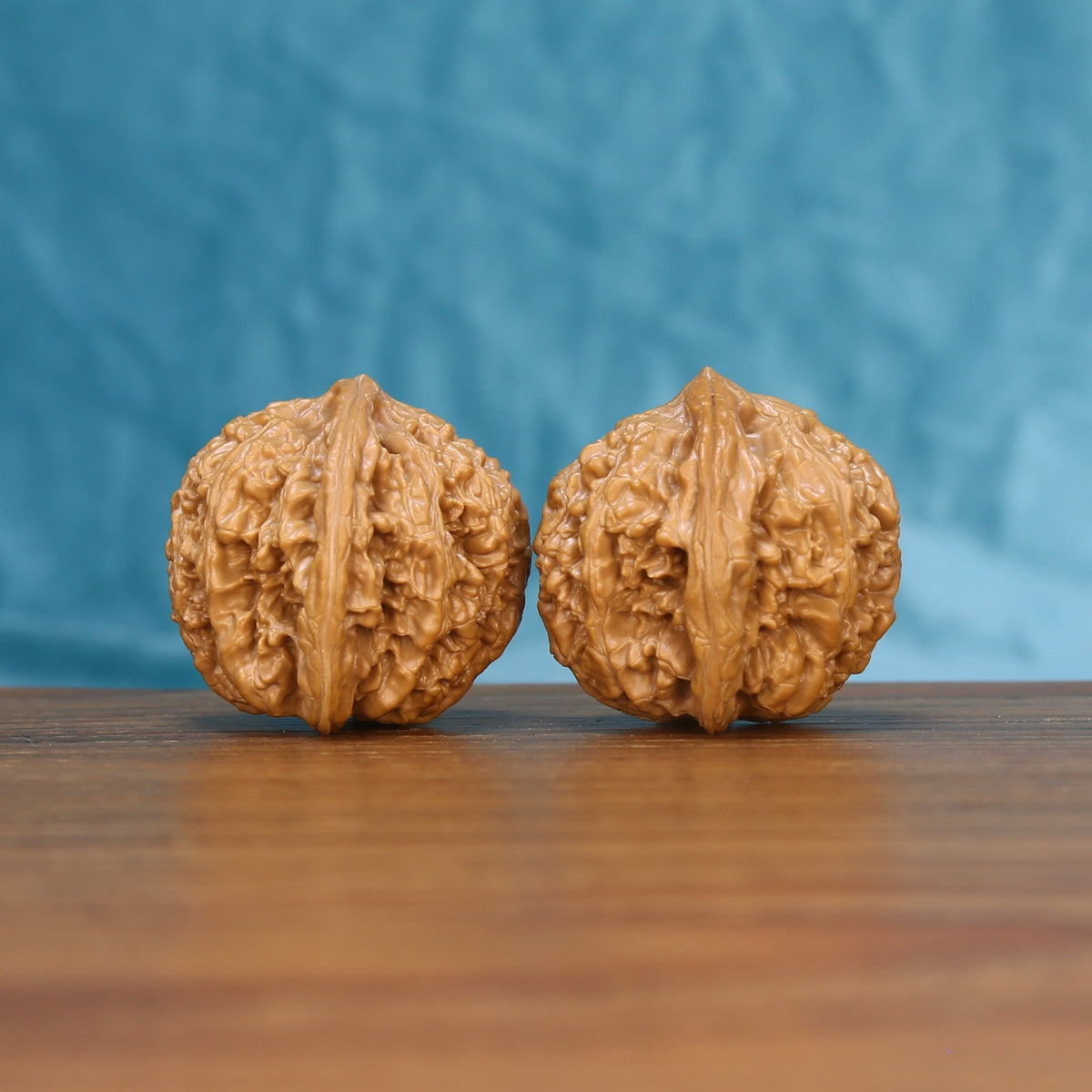 Three-quarter view of two Stone Wenwan walnuts with deep natural ridges

