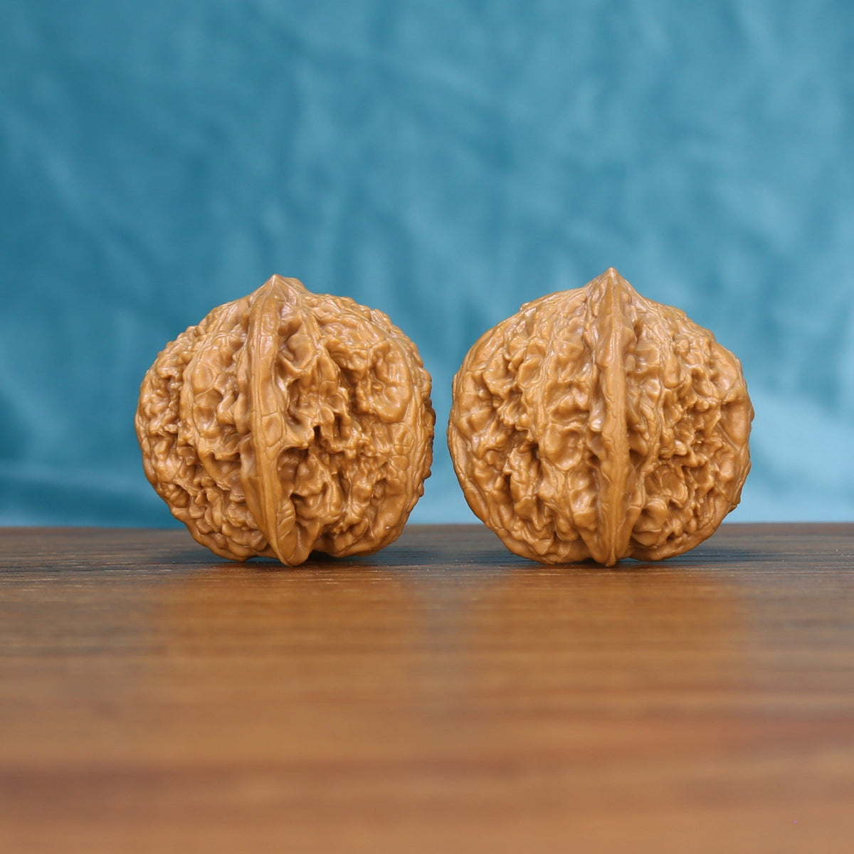 Side view of a Stone Wenwan walnut pair on a wooden surface
