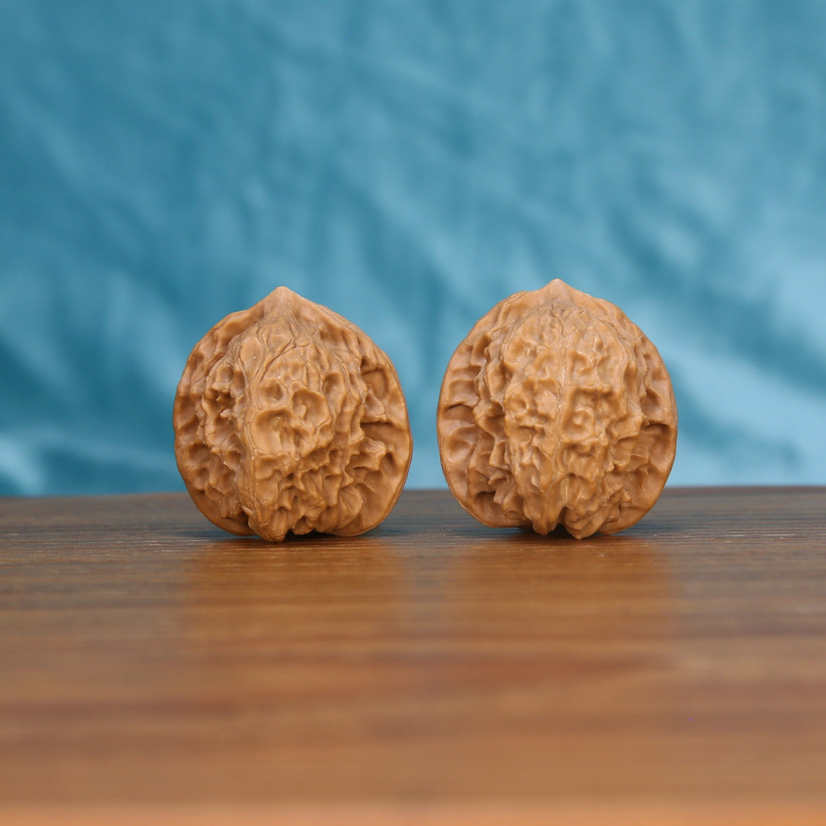 Ling-Long walnut set side profile on wood, blue background – deep carved labyrinth grain detail
