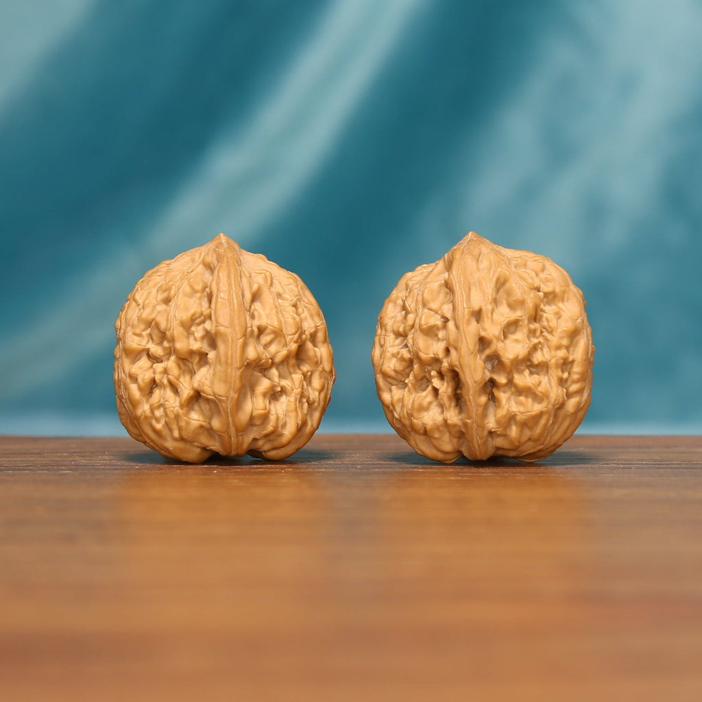 Side view of The Pocket Pebbles Wenwan walnuts highlighting their compact profiles and textured surfaces.
