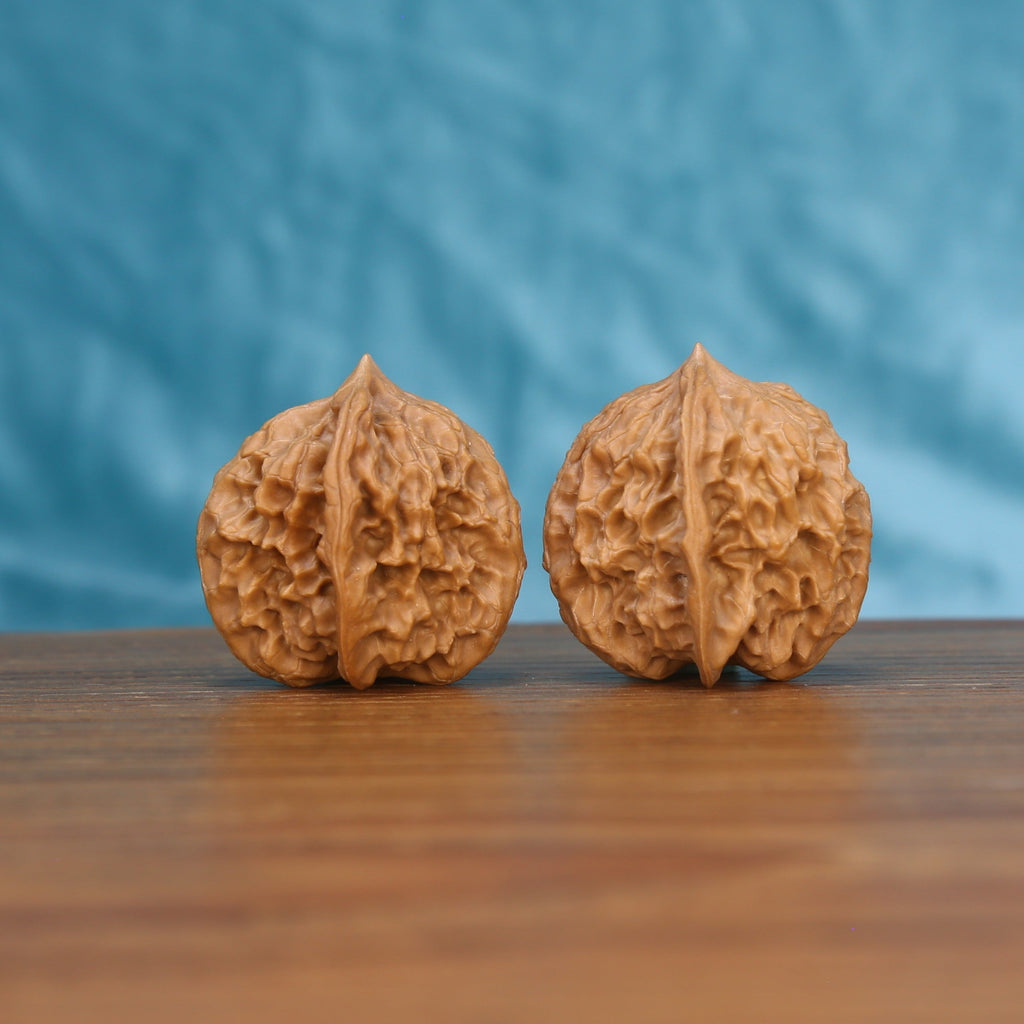 Single Ling-Long wenwan walnut on wooden surface, blue background – intricate carved labyrinth natural texture