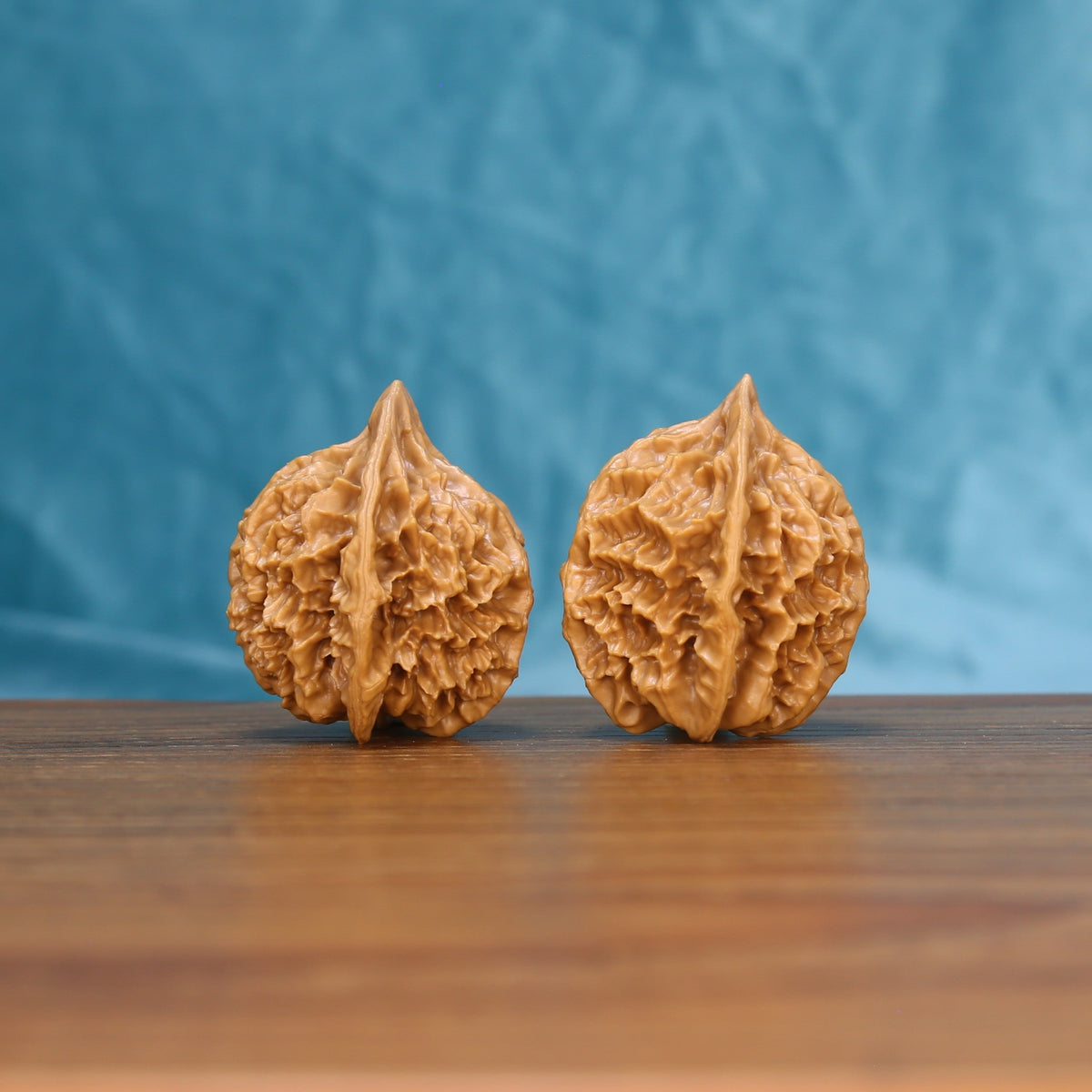 Close view of two matched Emperor wenwan walnuts showing sharp ridge carving and warm natural grain
