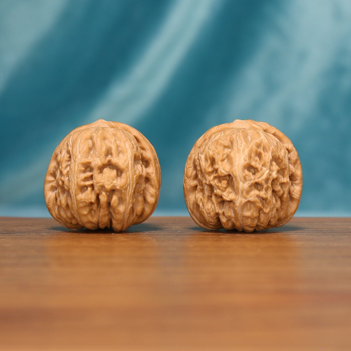 L16 Wenwan walnut matched pair displayed side by side on a wooden surface against a teal background.

