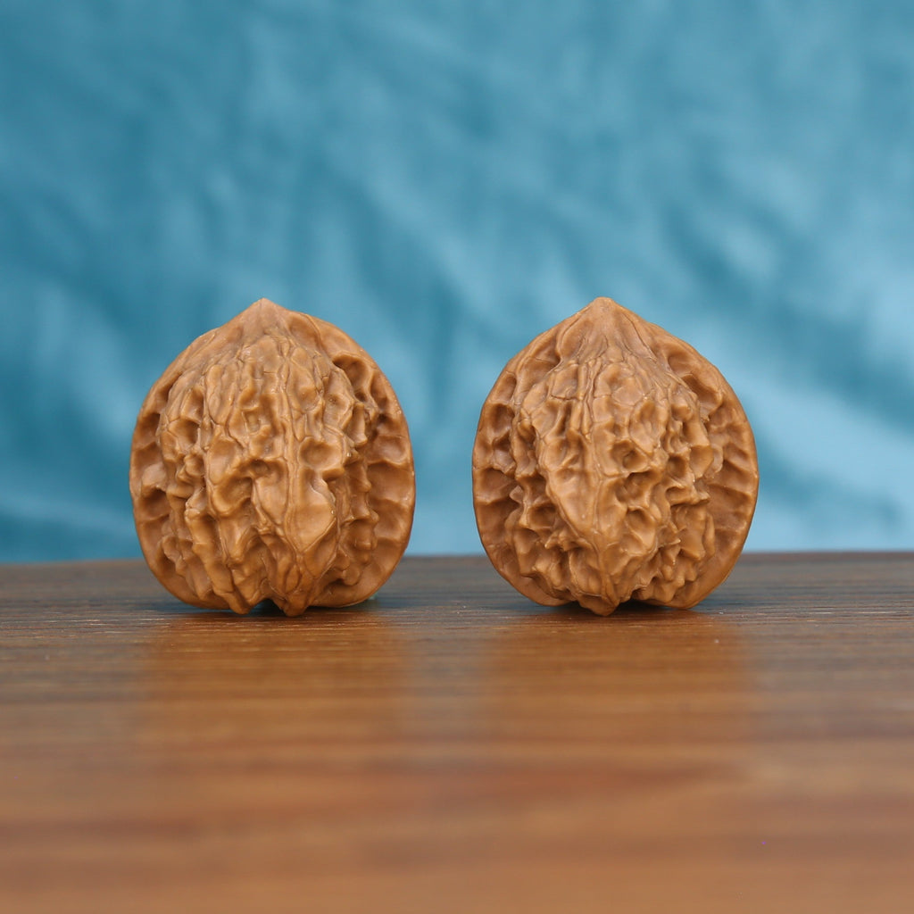 Two Ling-Long wenwan walnuts on wooden surface, blue fabric background – matching exquisite enigma set
