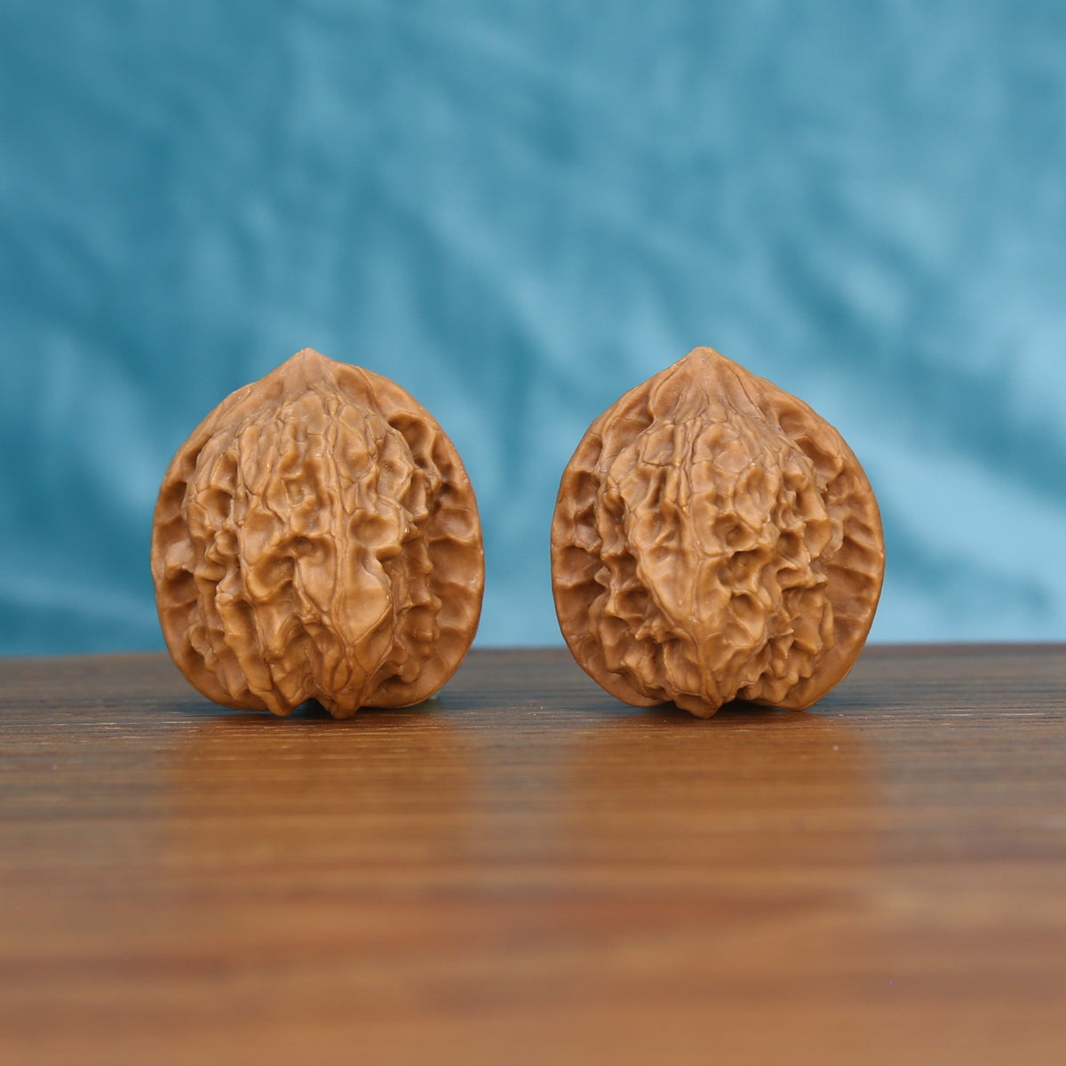 Two Ling-Long wenwan walnuts on wooden surface, blue fabric background – matching exquisite enigma set