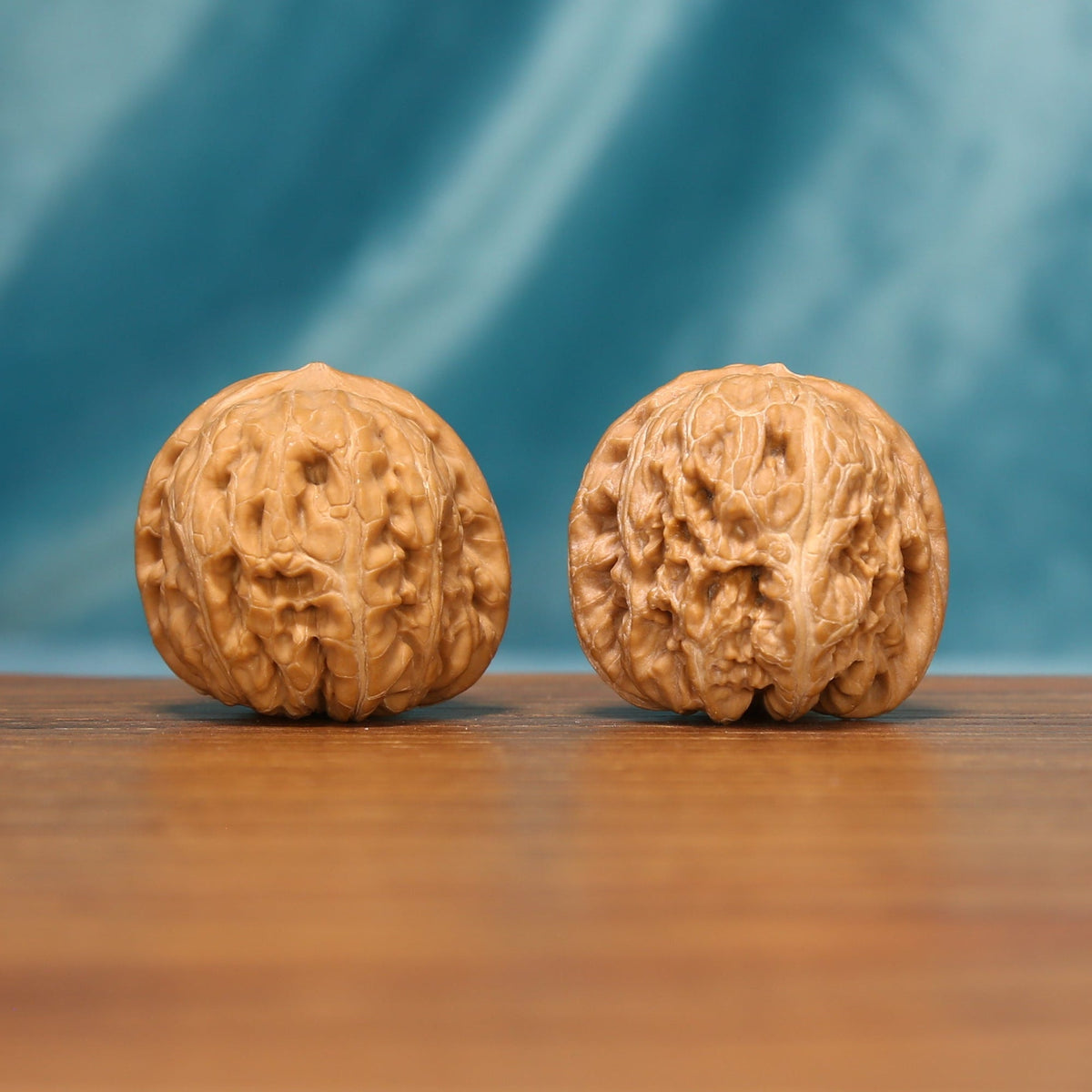 L16 Wenwan walnut pair shown from the front, highlighting rounded forms and natural ridge texture.
