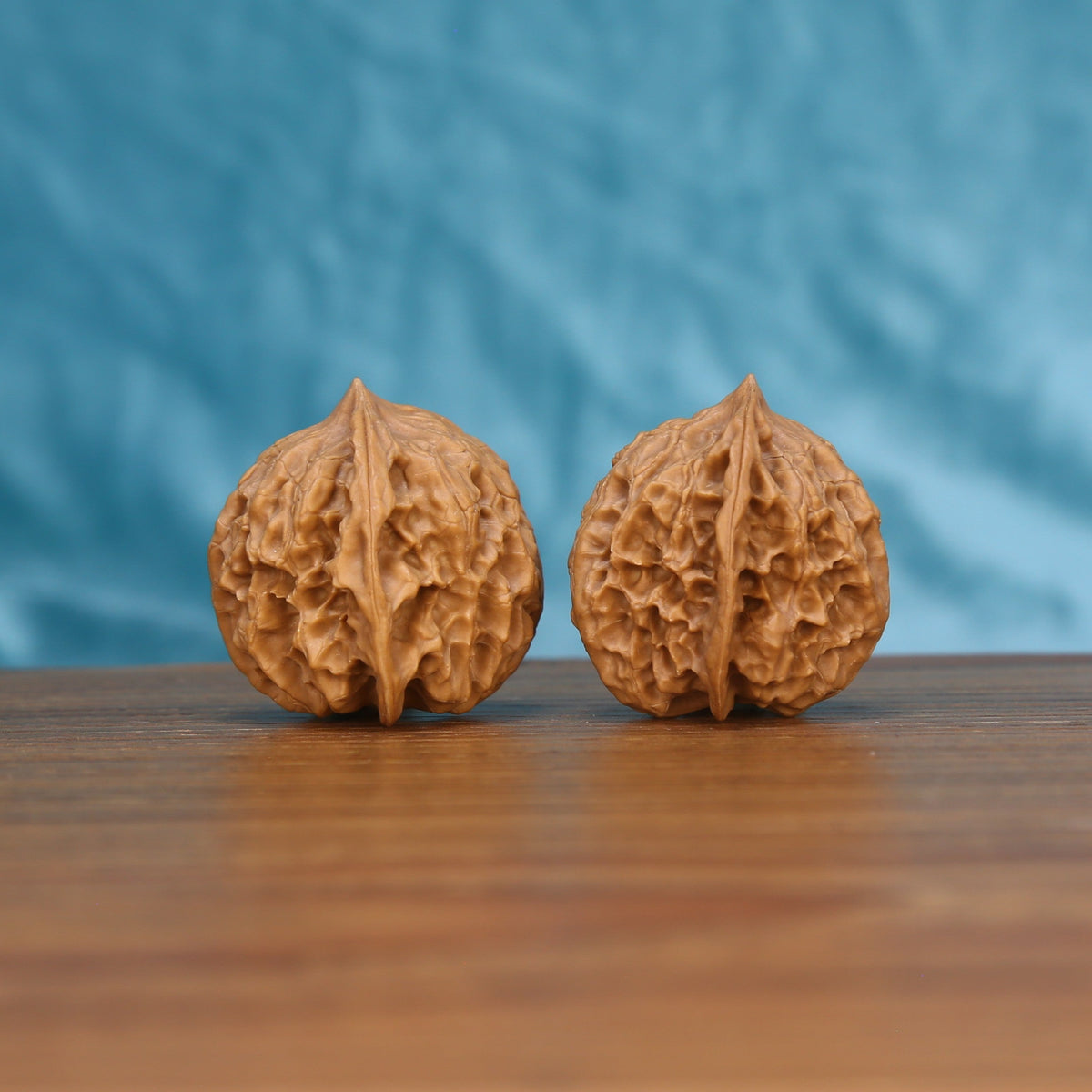 Single Ling-Long wenwan walnut on wooden surface, blue background – intricate hollow-carved natural texture close-up