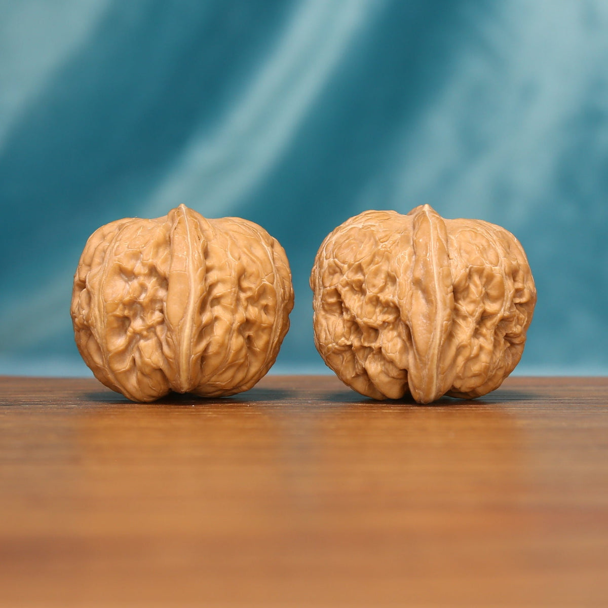 L16 Wenwan walnut matched pair shown from an angled front view, displaying detailed ridges and textured shells.
