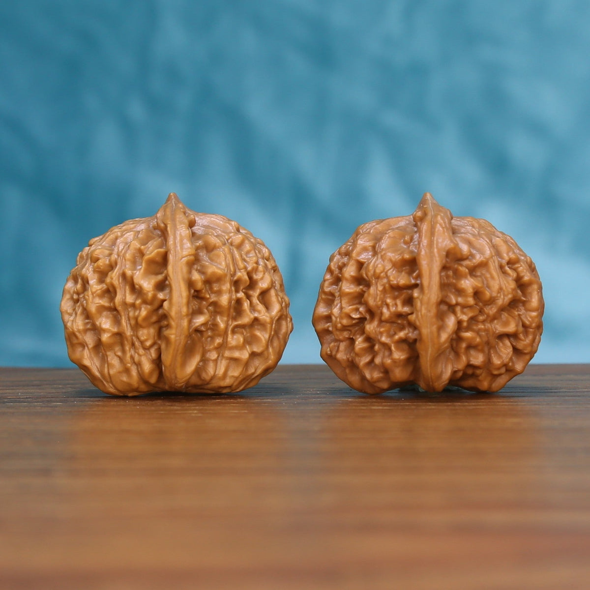 Three-quarter view of a Qinhuangdao Yuanbao Wenwan walnut pair on a wooden surface
