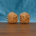 Angled front view of The Sandstone Pair Wenwan walnuts highlighting their rounded forms and dense natural ridges.
