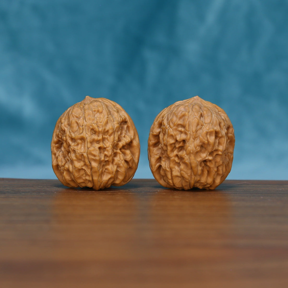 Side view of The Sandstone Pair Wenwan Walnut Set showing the walnuts’ full textured profiles and warm brown color.
