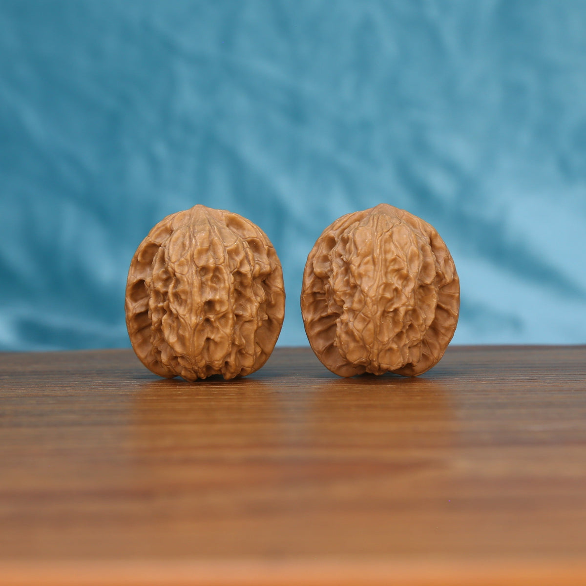 Two Chang-Men wenwan walnuts on wooden surface, blue fabric background – matching pagoda set