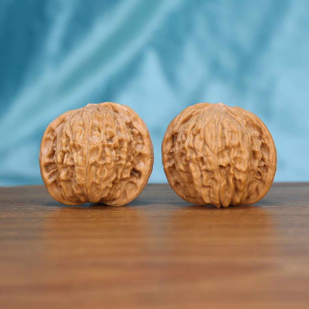 Two Mo-Pan wenwan walnuts displayed on wooden surface, blue fabric background – matching pair

