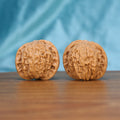 Two Mo-Pan wenwan walnuts displayed on wooden surface, blue fabric background – matching pair

