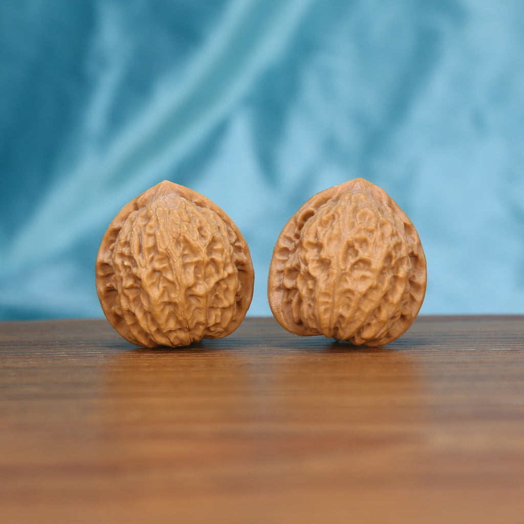 Two Xiao-Jin-Niu wenwan walnuts on wooden surface, blue fabric background – matching resolute taurus set