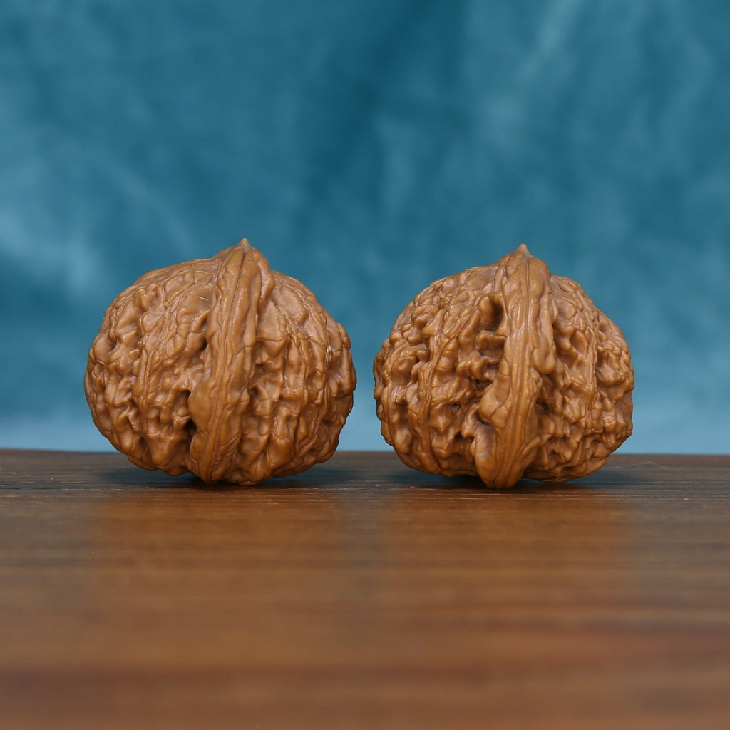 Detailed side view of The Bronze Relics Wenwan walnuts with pronounced vertical ridges and natural variation.
