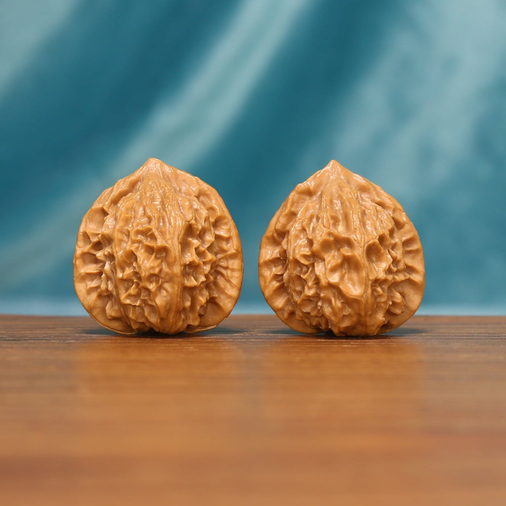 Angled front view of The Crowned Rounds Wenwan walnuts showing their rounded profiles and detailed textured surfaces.

