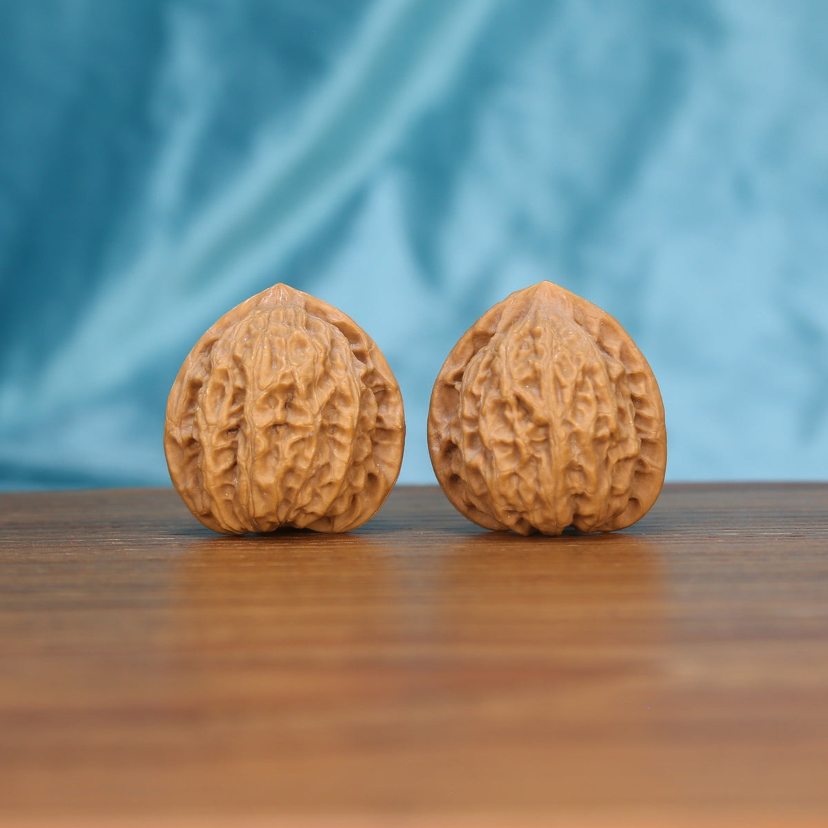 Xiao-Jin-Niu walnut set side profile on wood, blue background – golden bull grain detail