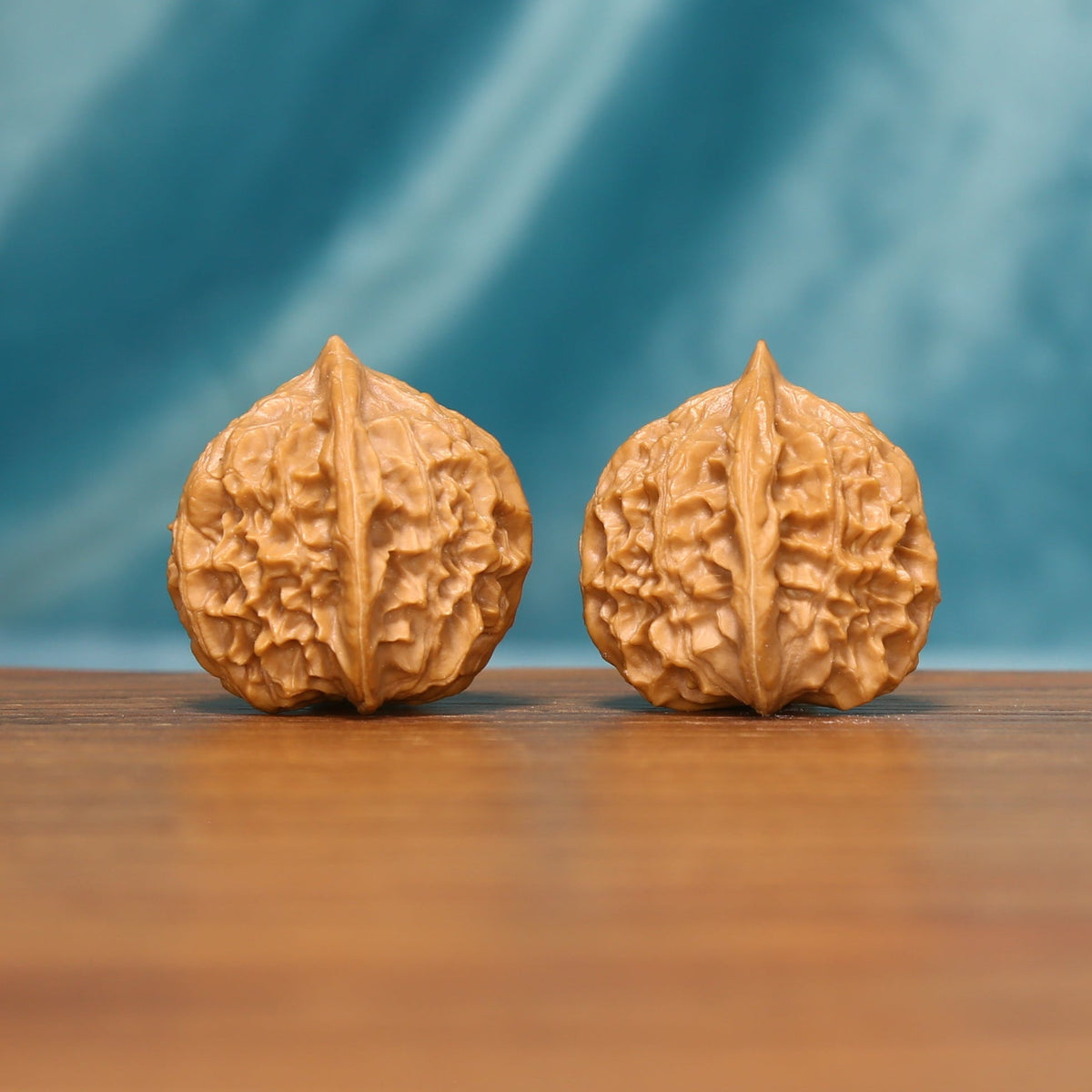 Detailed side view of The Crowned Rounds Wenwan walnuts with symmetrical textured surfaces and natural color.
