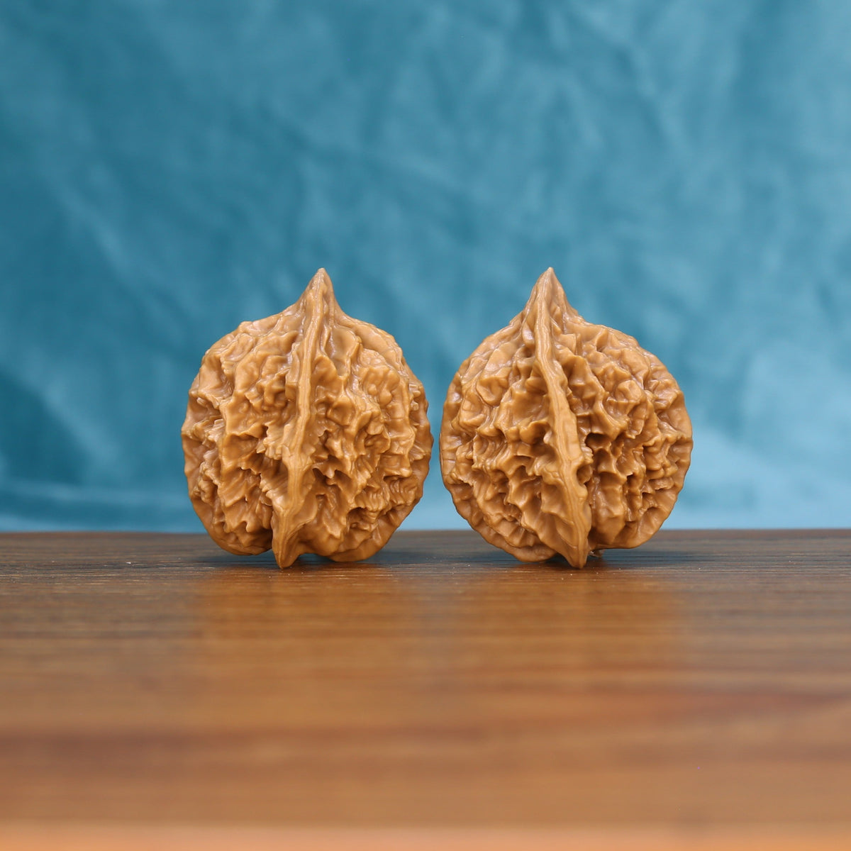 Close view of two matched Emperor wenwan walnuts showing sharp ridges and warm natural grain

