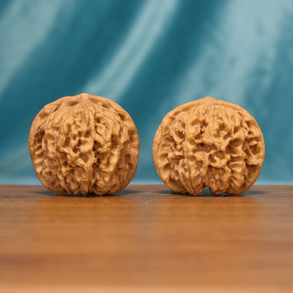 L19 Wenwan walnut pair shown from the front, highlighting rounded forms and dense natural ridge texture.
