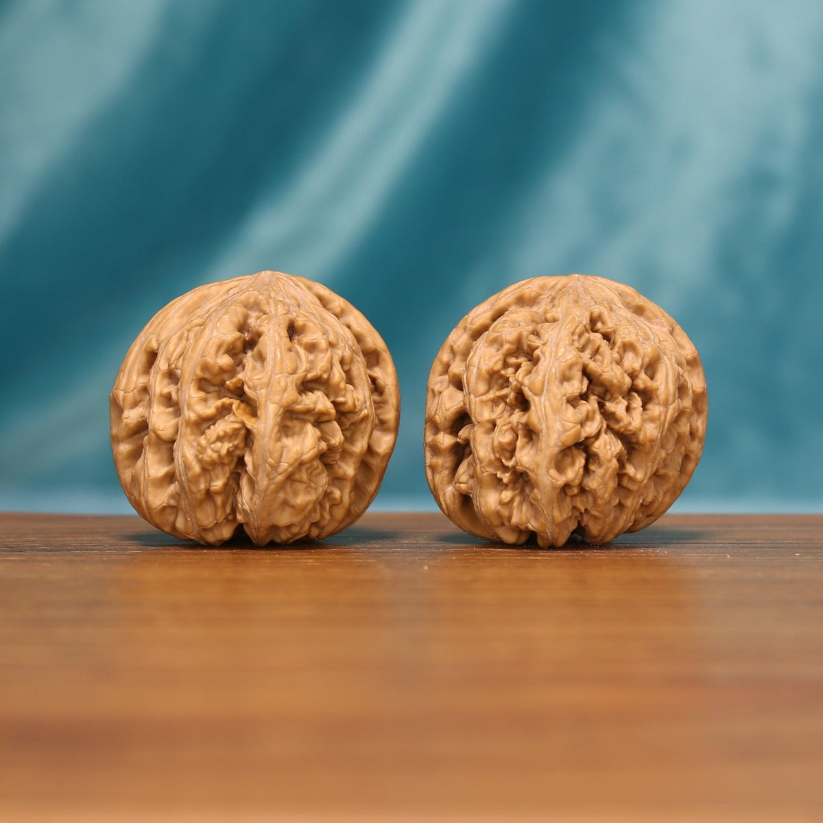 Angled front view of The Carved Twins Wenwan walnuts highlighting their broad forms and intricate textured surfaces.
