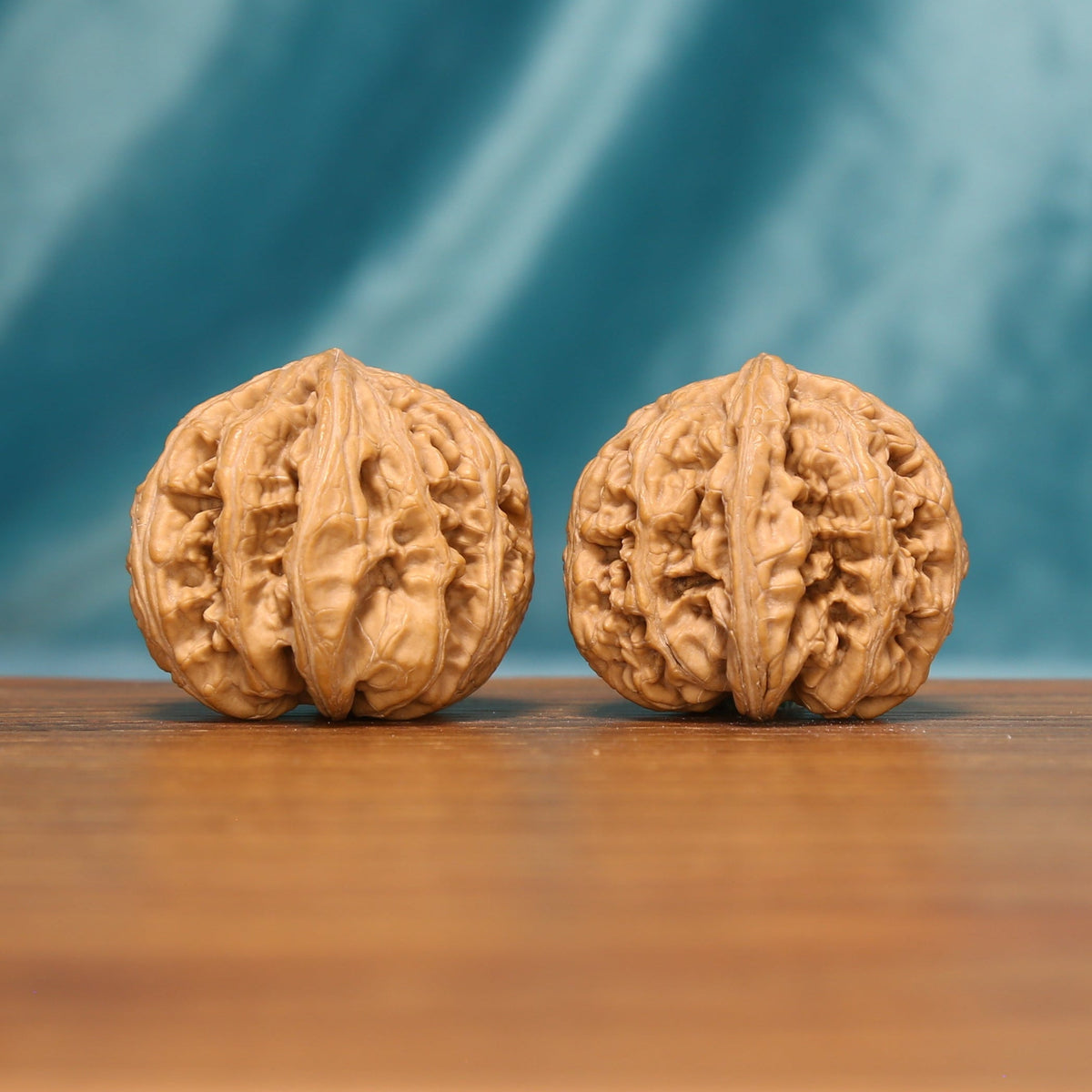 Side view of The Carved Twins Wenwan Walnut Set showing the walnuts’ dense ridge patterns and warm natural color.
