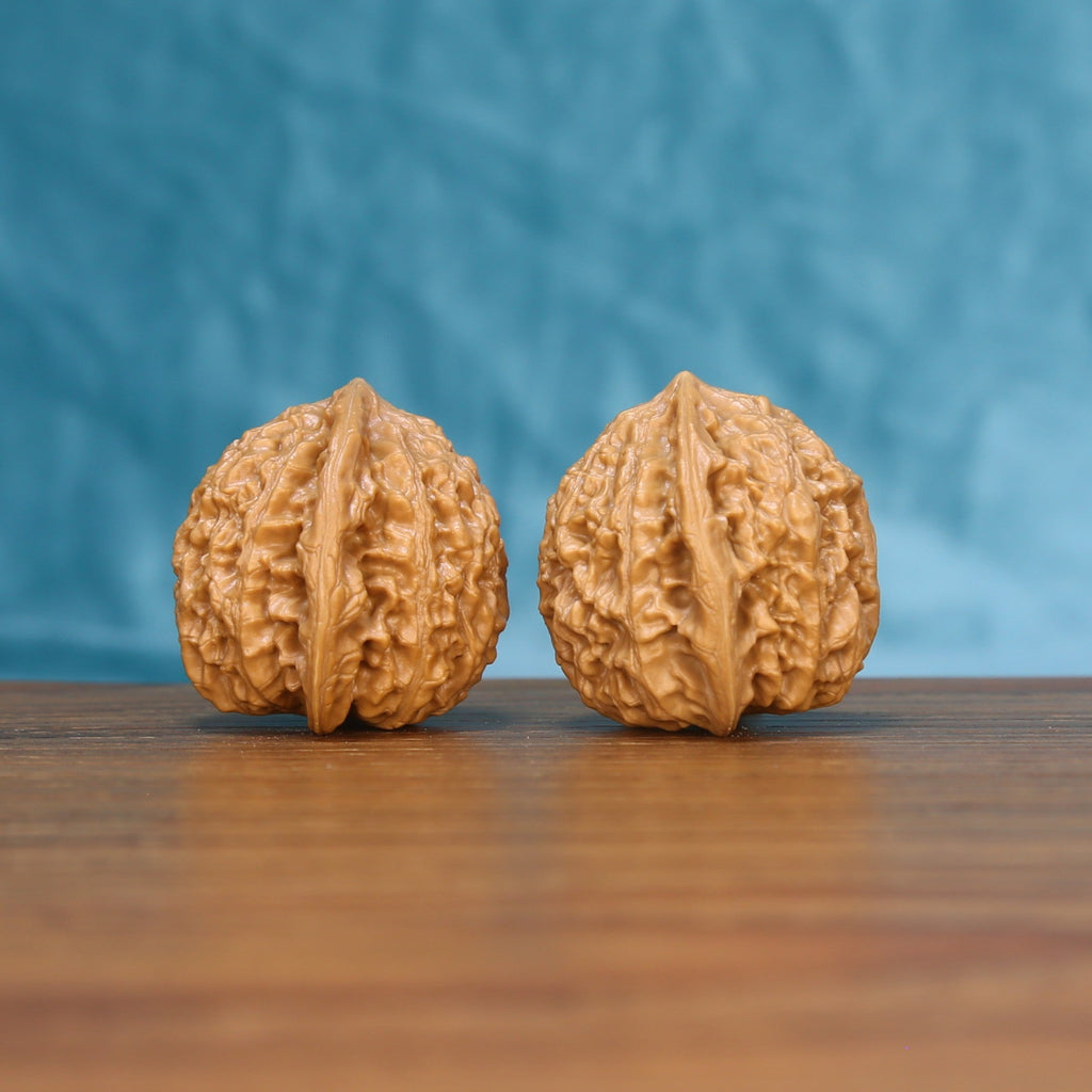 Close view of two matched Little Golden Ox wenwan walnuts showing detailed ridges and golden natural grain
