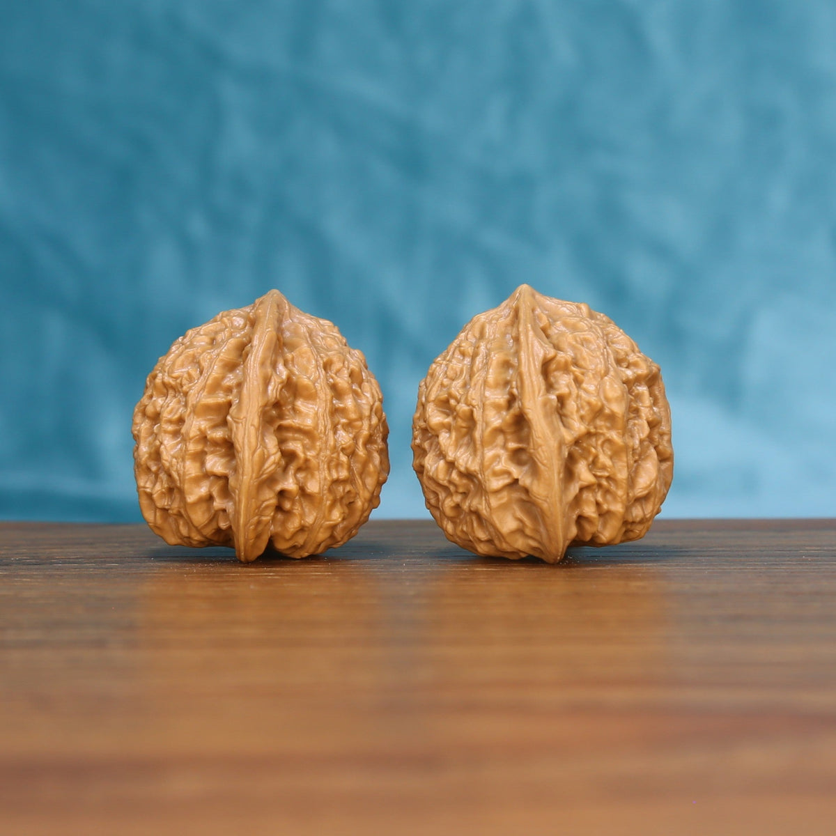 Close view of two matched Little Golden Ox wenwan walnuts showing detailed ridges and golden natural grain
