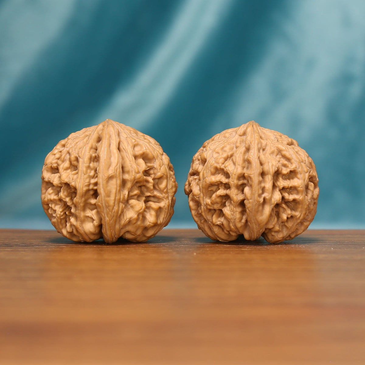 Detailed side view of The Carved Twins Wenwan walnuts with pronounced carved ridges and distinctive natural texture.
