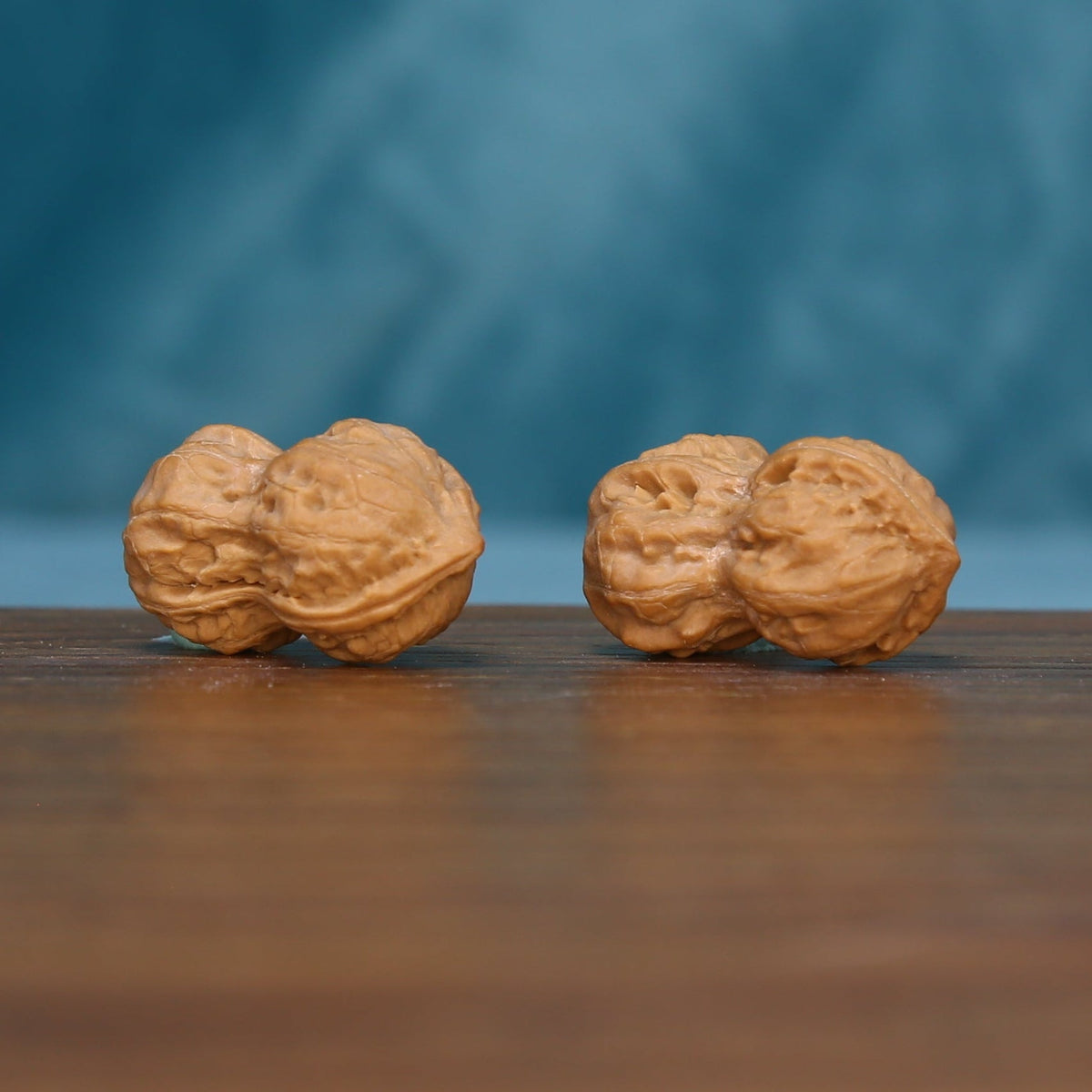 Side view of two L44 Peanut Gourd wenwan walnuts with textured tan surfaces
