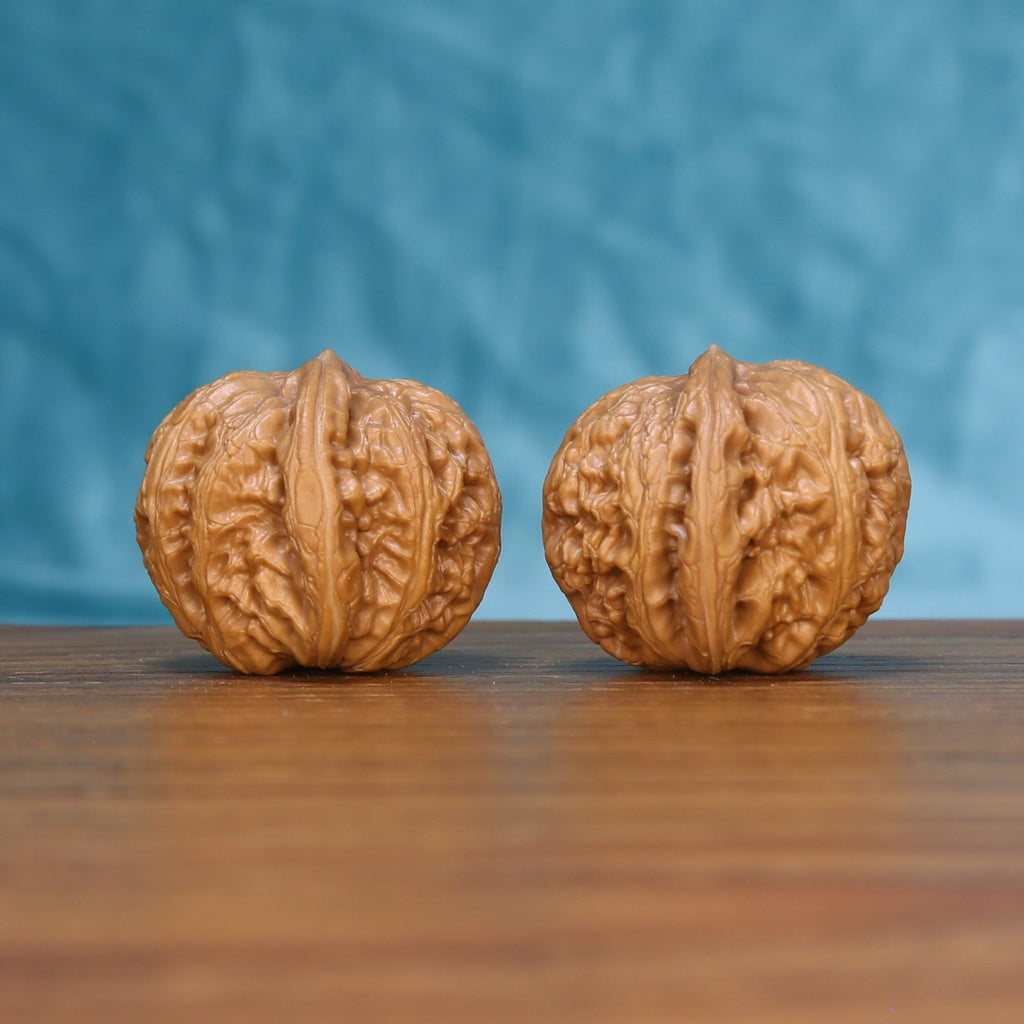 Close view of two matched Pinggu Ingot wenwan walnuts showing deep ridges and warm natural grain

