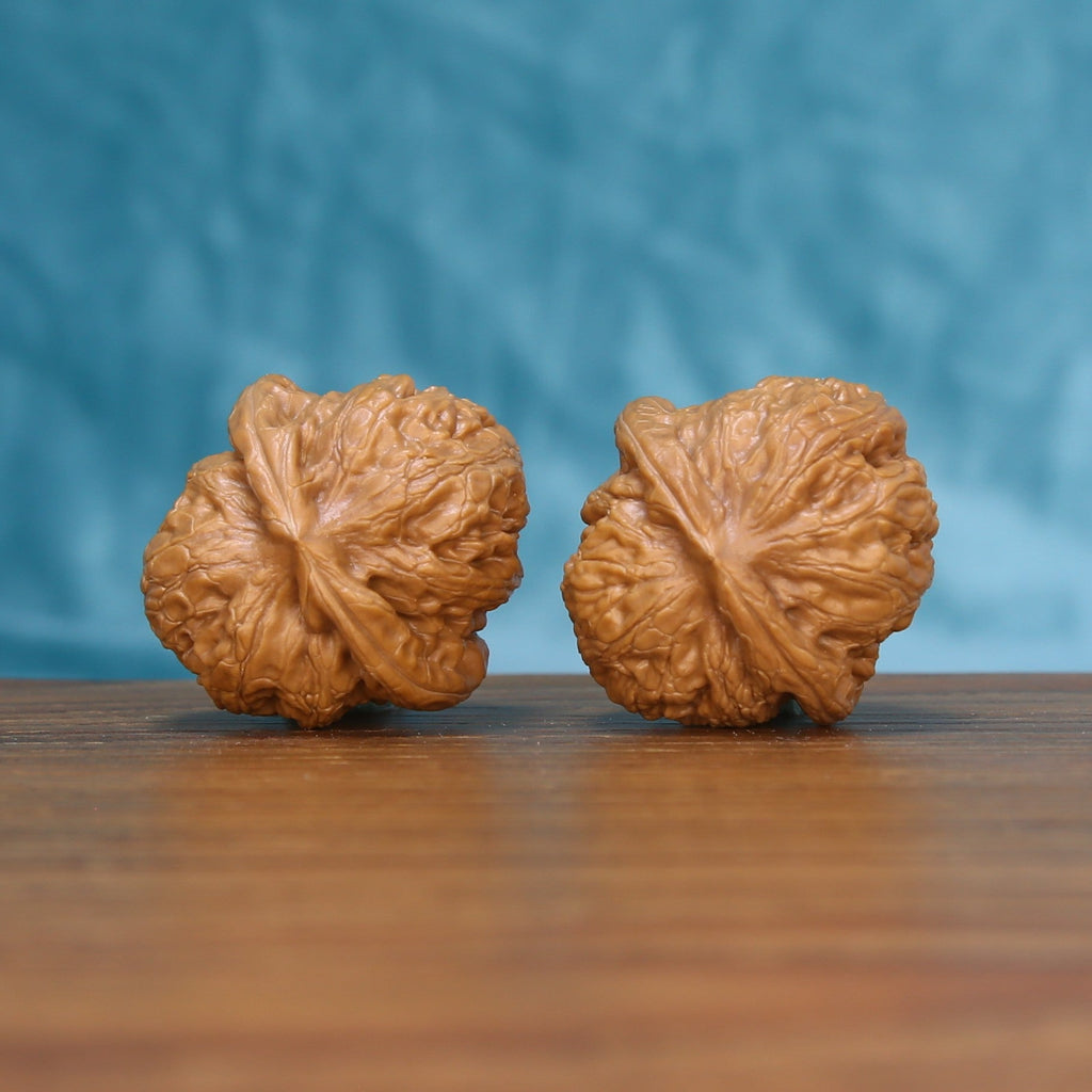 Side profile of the 6143 Pinggu Ingot wenwan walnut pair showing the low rounded silhouette

